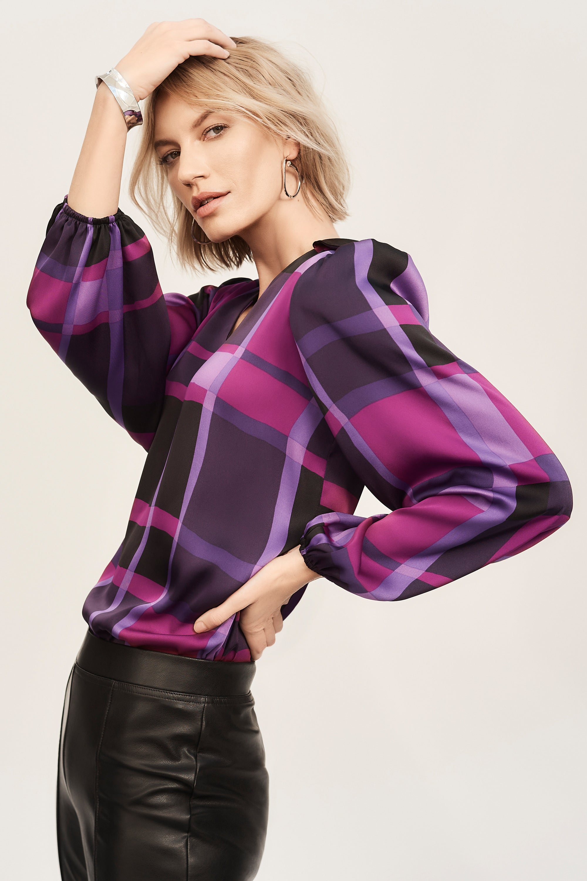 The essence of contemporary style, this satin top carries undeniable charm. The design features an alluring abstract plaid print that highlights your flair for great fashion. The long, puffed sleeves with elastic cuffs add a dramatic touch while the boxy silhouette offers both a comfortable, yet chic feel. The V-shaped neckline boasts a sleek shirt collar accentuating the garment’s poised look.