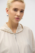 Load image into Gallery viewer, The definition of sporty chic, this Joseph Ribkoff hooded nylon jacket adds a trendy edge to your look. Featuring unexpected short dolman sleeves, front flap pockets, and a front zipper closure, it’s designed with a pleated back hem for added flair. An adjustable bungee cord lets you customize the relaxed fit to your liking.